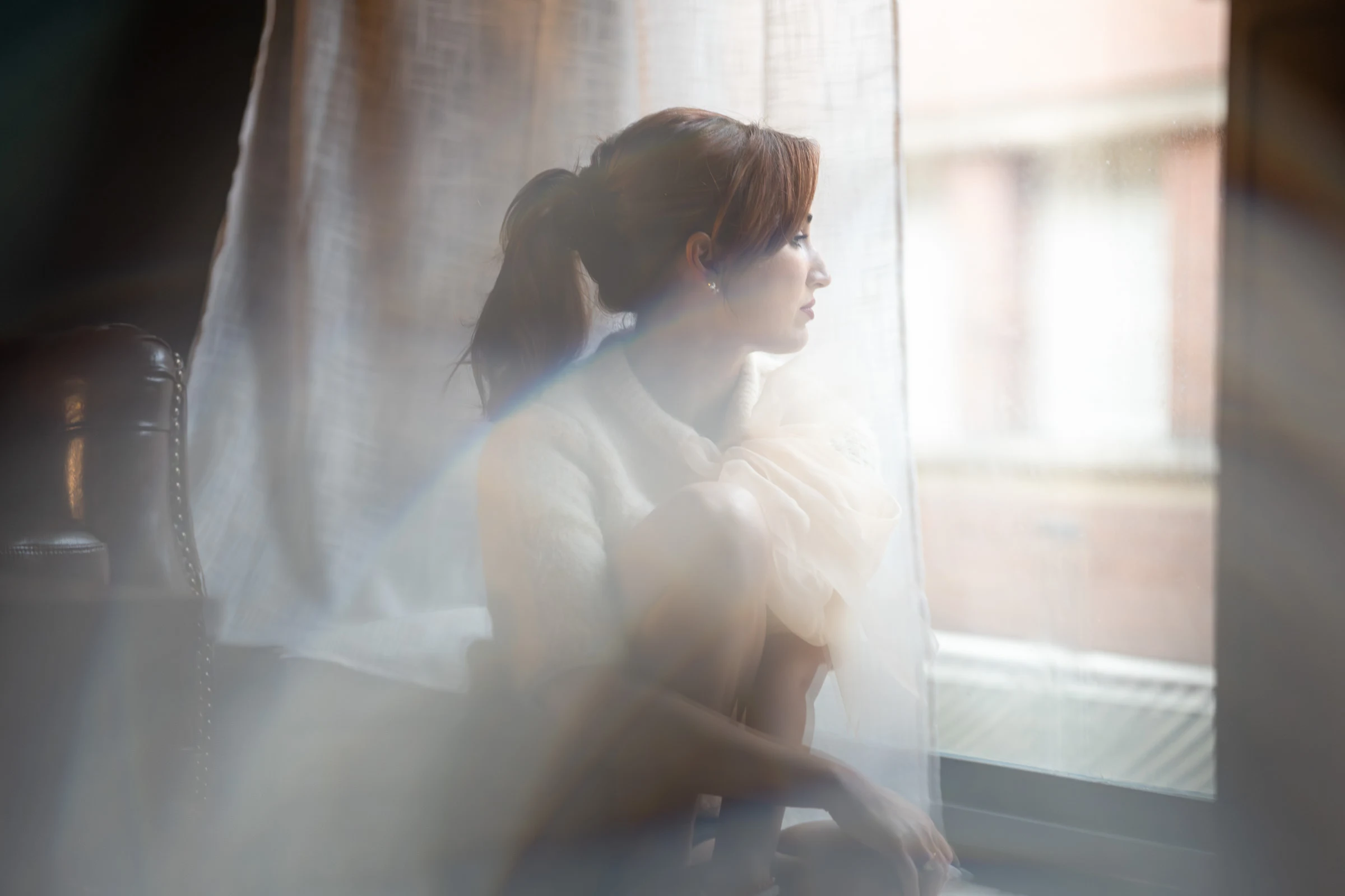 Portrait derrière un voilage de fenêtre